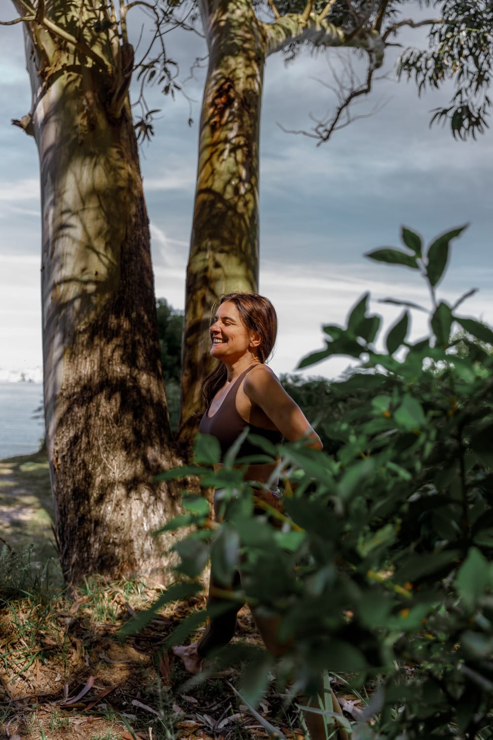 Fernanda sonriendo entre árboles junto al mar